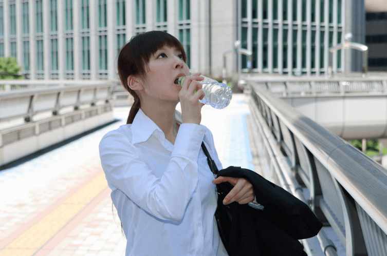 喉が渇き水を飲む女性